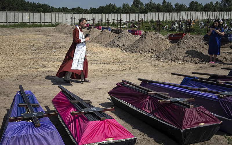 An Orthodox priest blesses coffins of civilians killed during Russia's occupation of Bucha, Ukraine
