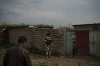 In this April 3, 2019 photo, an Iraqi army 20th division soldier waits outside a house during a patrol in the Badoush, Iraq area. A year and a half after the Islamic State group was declared defeated in Iraq, efforts to find remnants rely on intelligence operations, raids and searches for sleeper cells among the population. (AP Photo/Felipe Dana)
