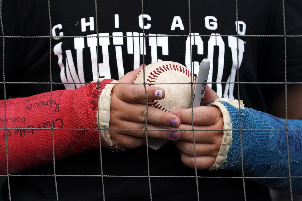 A fan holds a ball while waiting for autographs from players before a baseball game between the Arizona Diamondbacks and the Chicago White Sox in Chicago, Sunday, Aug. 28, 2022. (AP Photo/Nam Y. Huh)