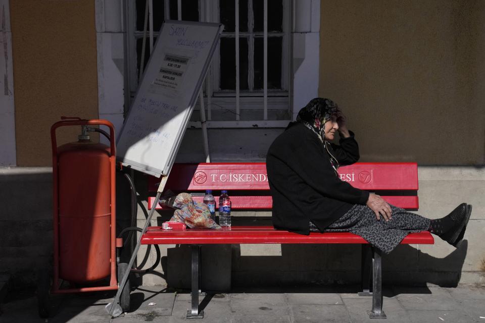 A woman sits on a bench of a train station in Iskenderun city, southern Turkey, Tuesday, Feb. 14, 2023. Thousands left homeless by a massive earthquake that struck Turkey and Syria a week ago packed into crowded tents or lined up in the streets for hot meals as the desperate search for survivors entered what was likely its last hours. (AP Photo/Hussein Malla)