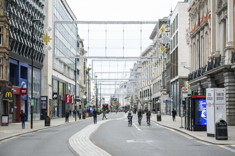 Cyclists ride along a quiet Oxford Street, London, where the majority of shops are closed as England continues a four week national lockdown to curb the spread of coronavirus, Saturday, Nov. 21, 2020. (Dominic Lipinski/PA via AP)