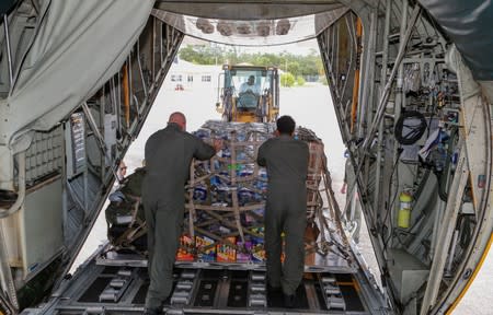 U.S. Coast Guardsmen unload relief supplies for Hurricane Dorian victims from their C-130 aircraft in Andros