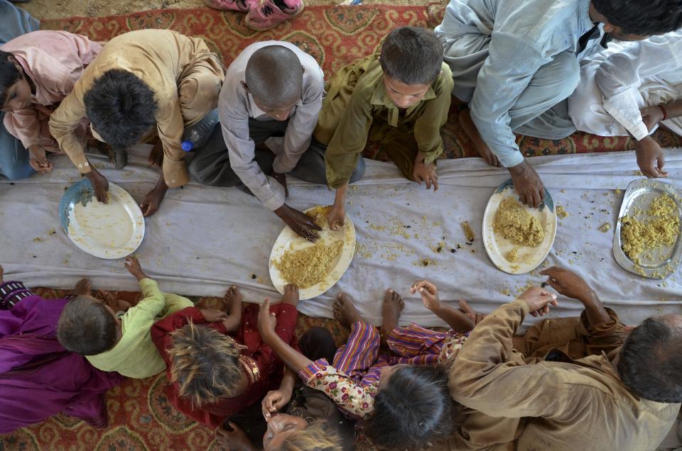 Children eat food provided by a charity group, in Jaffarabad, a flood-hit district of Baluchistan province, Pakistan, Thursday, Sept. 15, 2022. The devastating floods affected over 33 million people and displaced over half a million people who are still living in tents and make-shift homes. The water has destroyed 70% of wheat, cotton and other crops in Pakistan. (AP Photo/Zahid Hussain)