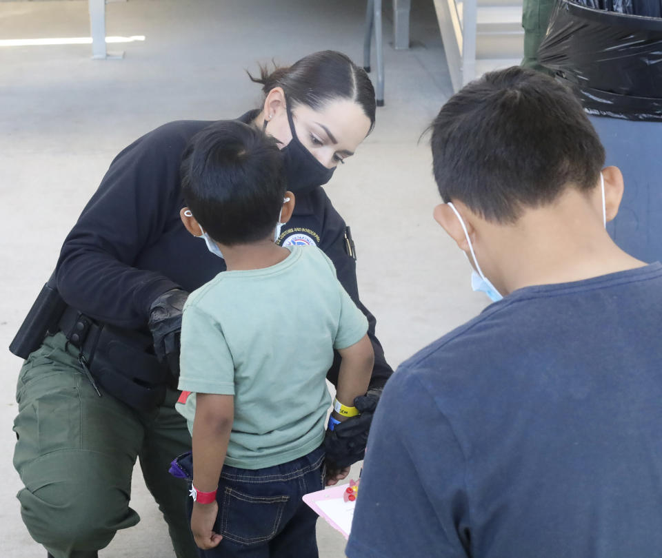 This May 4, 2021, photo provided by The U.S. Border Patrol shows a U.S. Border Patrol Processing Coordinator places a color-coded arm band on an underaged child at the Central Processing Center in El Paso, Texas. The Border Patrol says agents spend about 40% of their time on custody care and administrative tasks that are unrelated to border security, creating a staffing challenge. (U.S. Border Patrol via AP)