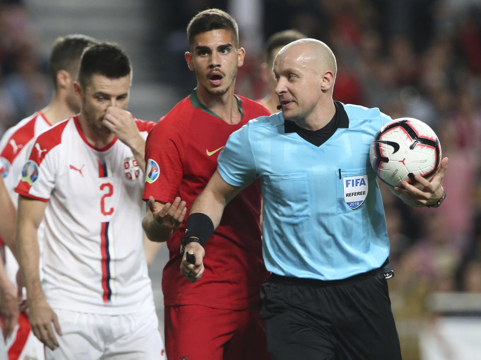 Referee Szymon Marciniak holds the ball during the Euro 2020 group B qualifying soccer match between Portugal and Serbia at the Luz stadium in Lisbon, Portugal, Monday, March 25, 2019. (AP Photo/Armando Franca)