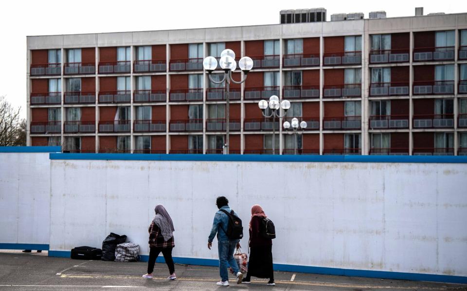 Asylum seekers enter the Crowne Plaza hotel through an exterior perimeter wall that has been installed whilst they stay at the hotel on