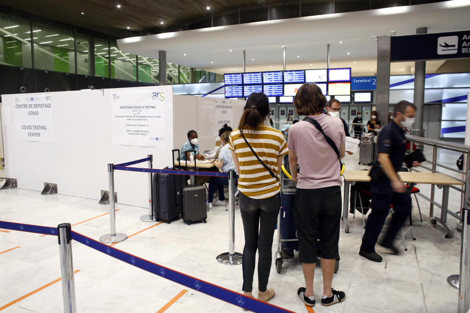 People register prior to be tested with the COVID-19 test, at the Roissy Charles de Gaulle airport, outside Paris, Saturday, Aug. 1, 2020. Travelers entering France from 16 countries where the coronavirus is circulating widely are having to undergo virus tests upon arrival at French airports and ports.(AP Photo/Thibault Camus)