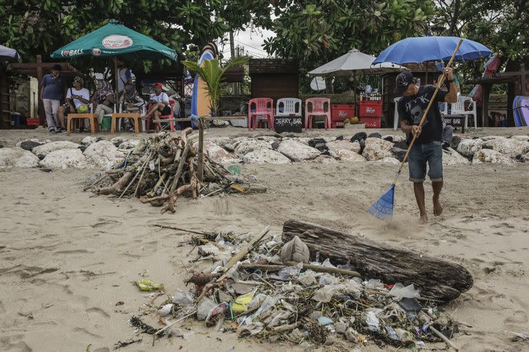 Lugareños limpian la playa durante la temporada de vacaciones en la playa de Kuta en Bali, Indonesia