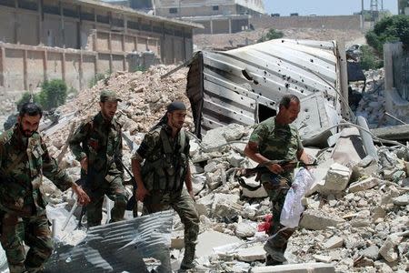 Forces loyal to Syria's President Bashar al-Assad walk with their weapons past rubble after they advanced on the southern side of the Castello road in Aleppo, Syria, in this handout picture provided by SANA on July 28, 2016. SANA/Handout via REUTERS