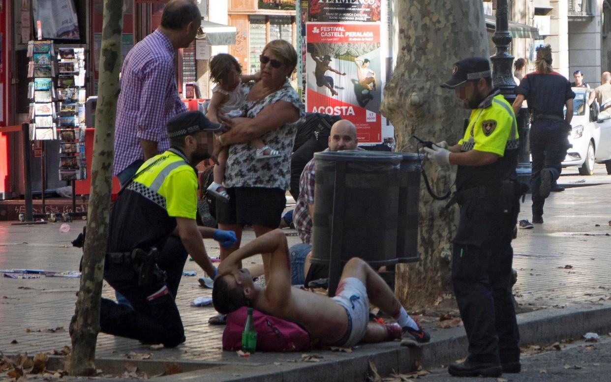 Police officers help the injured after a van crashed into pedestrians in Las Ramblas, downtown Barcelona - EPA