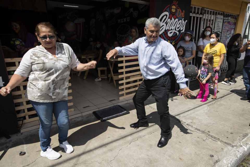 Fabio Rodolfo Vasquez dances with a customer at a promotional event outside a coffee shop on the outskirts of Guatemala City, Saturday, Sept. 19, 2020. Vasquez and his wife, Maria Moreno, entered an online dance contest during the new coronavirus pandemic to help them cope with the recent death of their daughter — and won it. (AP Photo/Moises Castillo)