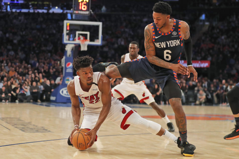 New York Knicks' Elfrid Payton, right, jumps over Miami Heat's Jimmy Butler as they scramble for a loose ball during the first half of the NBA basketball game, Sunday, Jan. 12, 2020, in New York. (AP Photo/Seth Wenig)