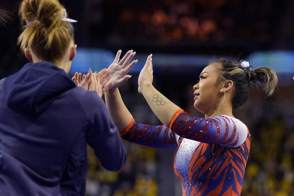 Auburn gymnast Sunisa Lee high fives teammates after performing during a meet at the University of Michigan, Saturday, March 12, 2022, in Ann Arbor, Mich. A record crowd came out to watch Lee, the reigning Olympic champion, and Auburn take on defending national champion Michigan. The arrival of Lee and several of her Olympic teammates at the collegiate level is helping fuel a spike in interest and participation in NCAA women's gymnastics. (AP Photo/Carlos Osorio)