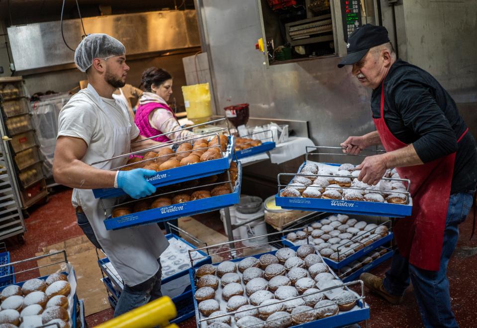 Bozek's Markets general manager Alex Bozek, left, and deli manager Janek Maslch, right, move around racks of paczkis as they are made ahead of Fat Tuesday at Bozek's Markets in Hamtramck on Monday, Feb. 12, 2024.