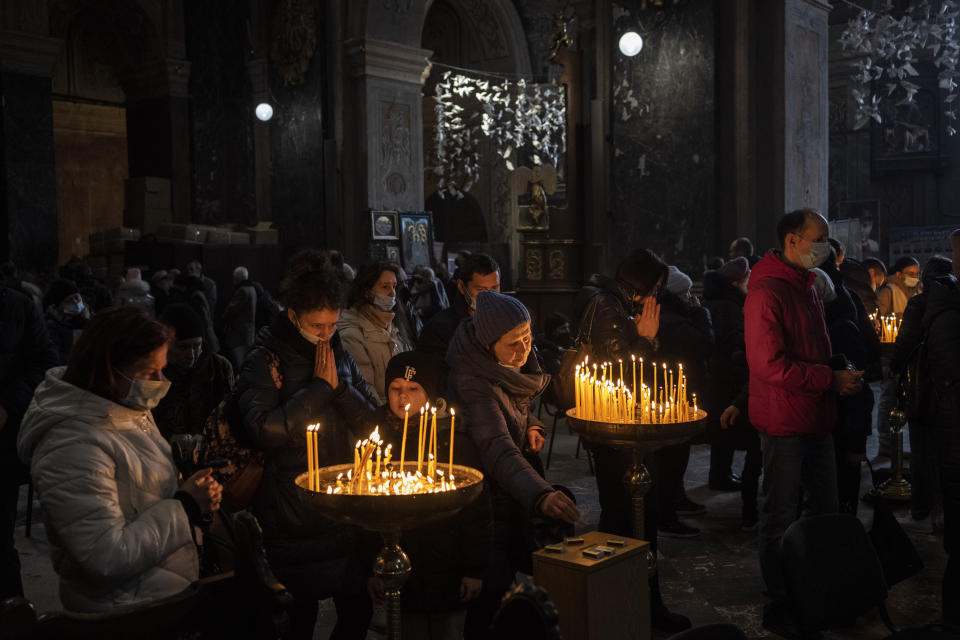 Christian worshipers light candles and pray after Sunday mass inside the Saints Peter and Paul Garrison Church in Lviv, western Ukraine, Sunday, March 6, 2022. (AP Photo/Bernat Armangue)