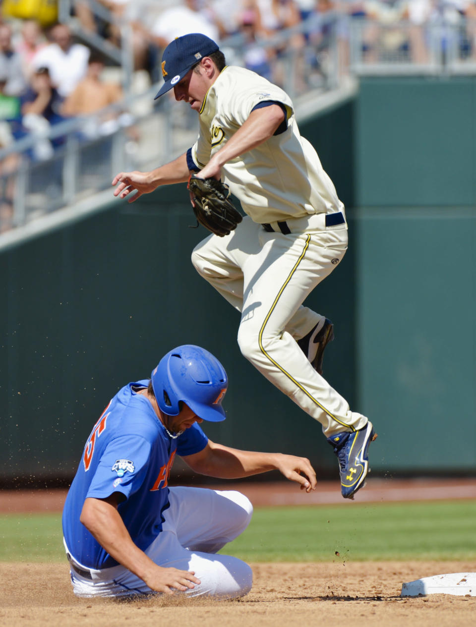 Florida's Brian Johnson, bottom, is safe at second base on a throwing error as Kent State shortstop Jimmy Rider leaps to avoid him in the second inning of an NCAA College World Series elimination baseball game in Omaha, Neb., Monday, June 18, 2012. (AP Photo/Ted Kirk)