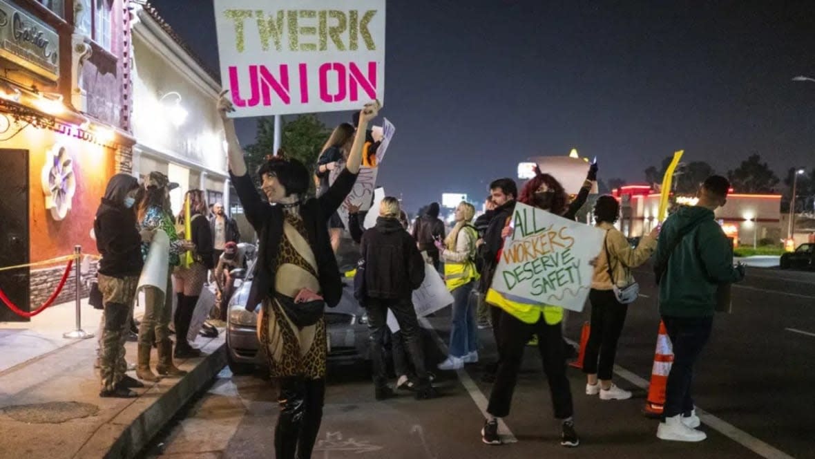 A protester identified as “Reagan” holds a sign outside the Star Garden Topless Dive Bar last March in the North Hollywood area of Los Angeles. Dancers at the bar, who have for 15 months been seeking safer workplace conditions, better pay and health insurance, among other benefits, are poised to become the only unionized group of strippers in America. (Photo: Francine Orr/Los Angeles Times via AP)
