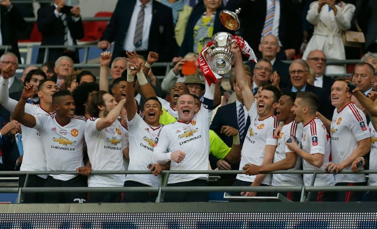 Manchester United's English striker Wayne Rooney (centre left) and English midfielder Michael Carrick lift the FA Cup trophy as players celebrate their 2-1 victory after extra time