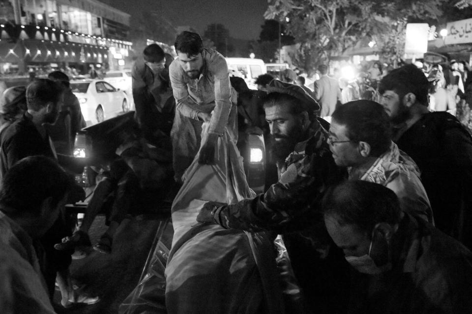 Volunteers and medical staff unload bodies from a pickup truck outside a hospital after two powerful explosions killed at least six people outside the airport in Kabul on Thursday.