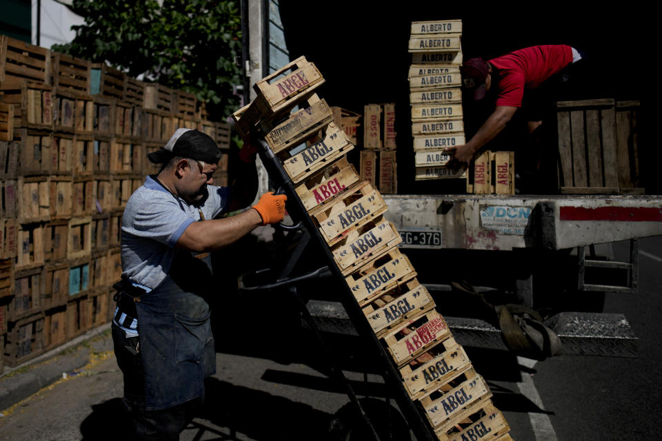 File - Dario Gomez, top right, and Darwin Perez load crates on a truck as they go to and from the main market to load up with produce to sell in Buenos Aires, Argentina, Monday, Dec. 11, 2023. South America's second largest economy is suffering 143% annual inflation. (AP Photo/Natacha Pisarenko, File)