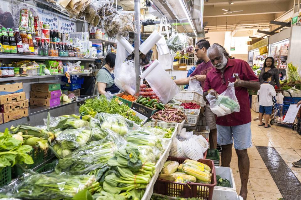A customer pays for fresh produce at Tekka Center in Singapore, on Saturday, April 22, 2023. (Edwin Koo/Bloomberg)