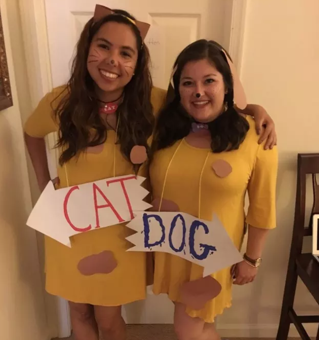 Two women hugging and wearing "Cat" and "Dog" signs