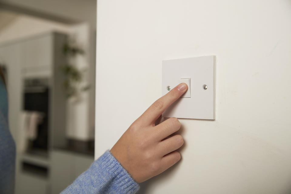 Person's finger pressing a light switch on a wall