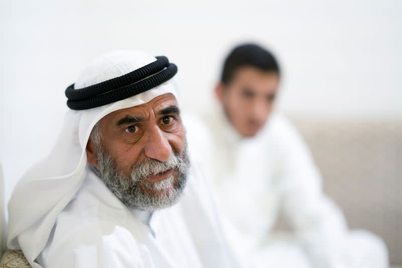 Abu Ahmad al-Enezi, a stateless sits with his son at their home in Sulaibiya