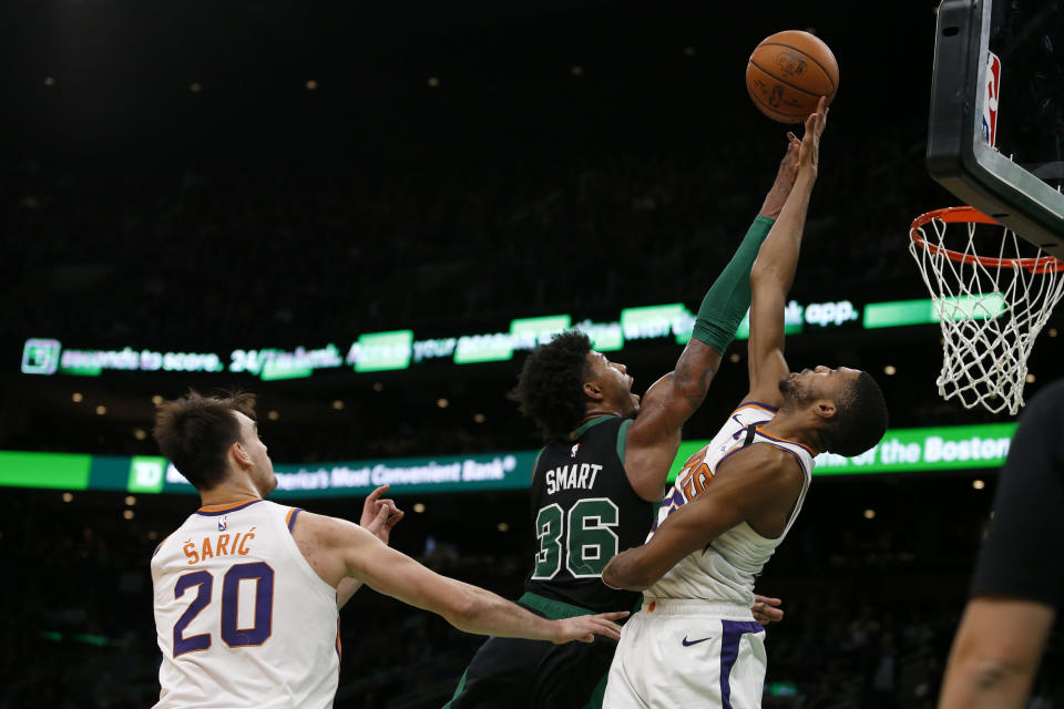 Phoenix Suns forward Mikal Bridges (25) blocks a shot by Boston Celtics guard Marcus Smart (36) as Suns forward Dario Saric (20) looks on during the second half of an NBA basketball game, Saturday, Jan. 18, 2020, in Boston. (AP Photo/Mary Schwalm)