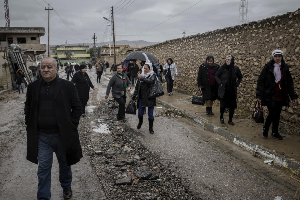 Christians walk in the rain to attend Christmas Eve's Mass in the Assyrian Orthodox church of Mart Shmoni, in Bartella, Iraq, Saturday, December 24, 2016. For the 300 Christians who braved rain and wind to attend the mass in their hometown, the ceremony provided them with as much holiday cheer as grim reminders of the war still raging on around their northern Iraqi town and the distant prospect of moving back home. Displaced when the Islamic State seized their town in 2014, they were bused into the town from Irbil, capital of the self-ruled Kurdish region, where they have lived for more than two years. (AP Photo/Cengiz Yar)
