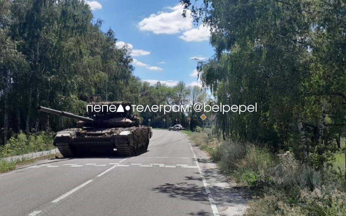 The tank moving past the half-squashed remains of a civilian car in the western Belgorod region of Russia