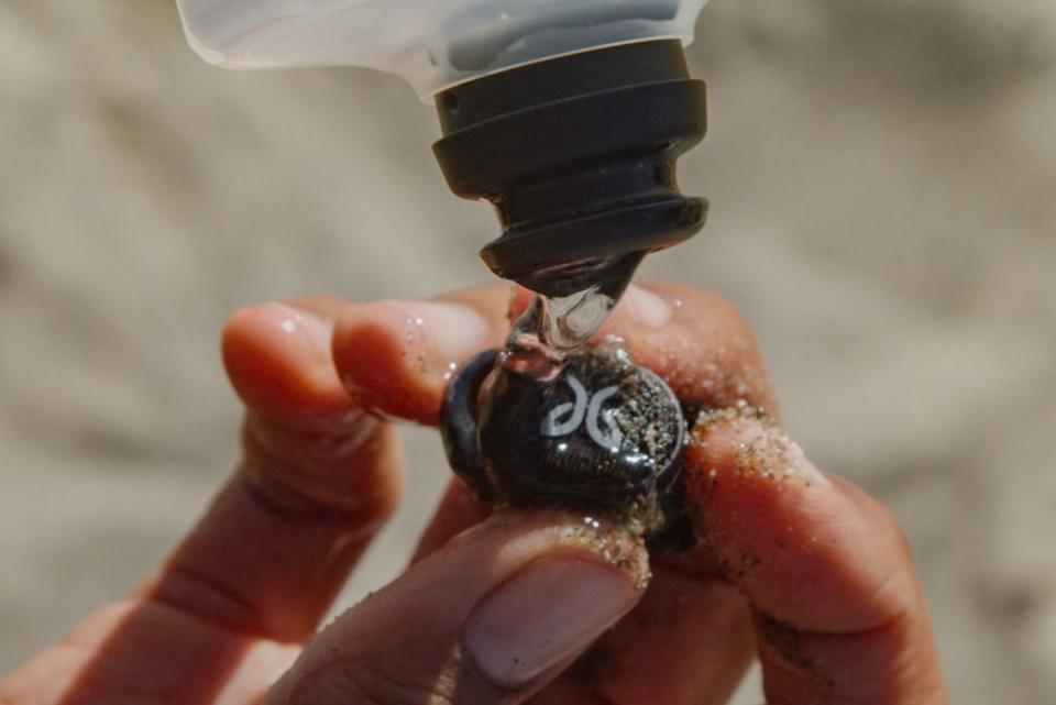 washing sand off a jaybird vista earbud with water from a bottle