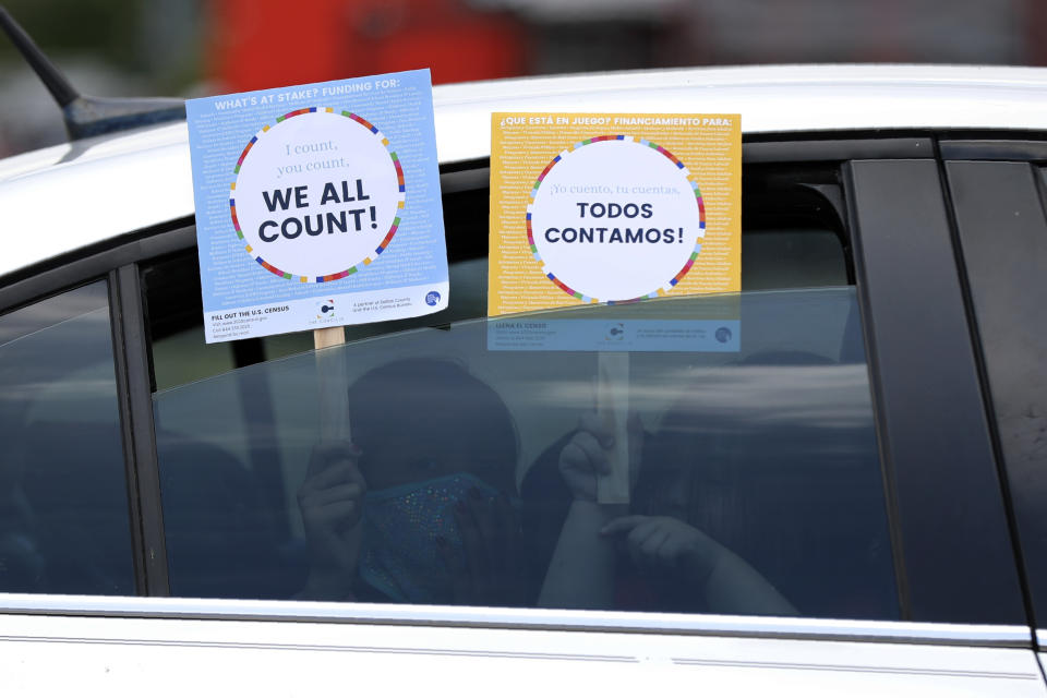 FILE - In this June 25, 2020, file photo, two young children hold signs through the car window that make reference to the 2020 U.S. Census as they wait in the car with their family at an outreach event in Dallas. Thousands of census takers are about to begin the most labor-intensive part of America’s once-a-decade headcount (AP Photo/Tony Gutierrez, File)