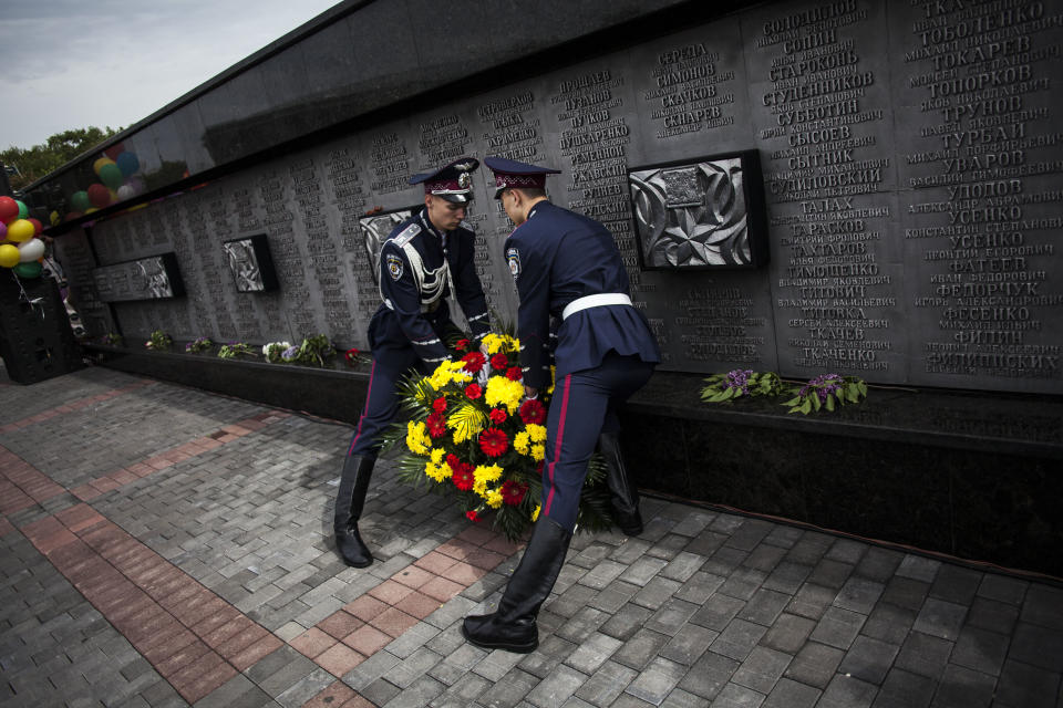 Ukrainian police officers lay a bouquet of flowers by a monument in memory of those fallen in WWII during the commemoration of Victory Day in Donetsk, Ukraine, Friday, May 9, 2014. Victory Day honors the armed forces and the millions who died in World War II. This year it comes as Russia is locked in the worst crisis with the West, over Ukraine, since the end of the Cold War. (AP Photo/Manu Brabo)