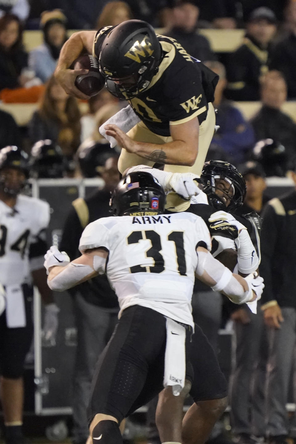 Wake Forest's Sam Hartman, top, tries to leap over Army's Leo Lowin (31) during the second half of an NCAA college football game in Winston-Salem, N.C., Saturday, Oct. 8, 2022. (AP Photo/Chuck Burton)