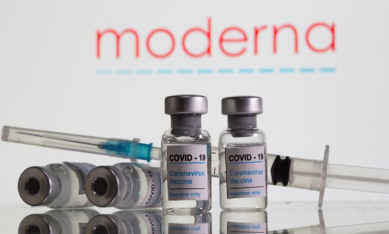 Vials labelled "COVID-19 Coronavirus Vaccine" and sryinge are seen in front of displayed Moderna logo in this illustration