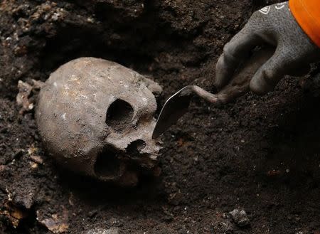 An archaeologist digs out skeletons from the site of the graveyard of the Bethlehem, or Bedlam, hospital next to Liverpool Street Station in the City of London in this file photo taken on August 7, 2013. REUTERS/Andrew Winning