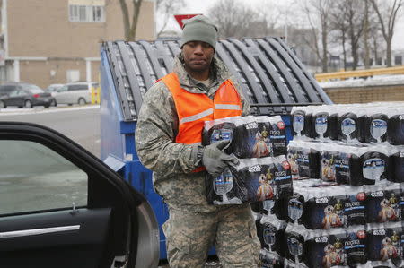 Michigan National Guard member David Brown helps to distribute water to a line of residents in their cars in Flint, Michigan January 21, 2016. REUTERS/Rebecca Cook