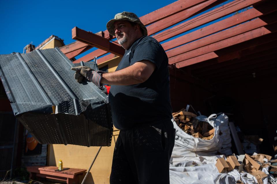 Jay Johnson, owner of Bubba's Roadhouse & Saloon and Bert's Bar & Grill, removes pieces of debris from the front of his restaurant after Hurricane Ian passed through the region Wednesday afternoon in Cape Coral, FL., on Friday, September 30, 2022.