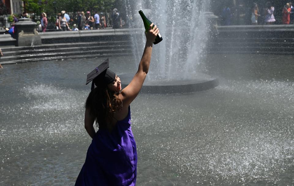 Student Annika Skuires drinks champagne in the fountain at Washington Square Park on May 19, 2021 in New York, after the New York University commencement ceremony was held virtually for the class of 2021. (Photo by TIMOTHY A. CLARY / AFP) (Photo by TIMOTHY A. CLARY/AFP via Getty Images)