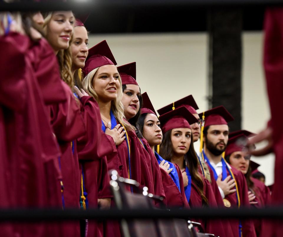 Graduates from Doherty Memorial High School stand for the national anthem during commencement exercises at the DCU Center Tuesday evening.