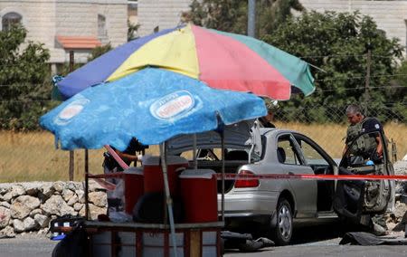 Israeli policemen inspect the scene of a Palestinian car-ramming attack at the entrance of Beit Einun village, near the West Bank city of Hebron July 18, 2017. REUTERS/Mussa Qawasma