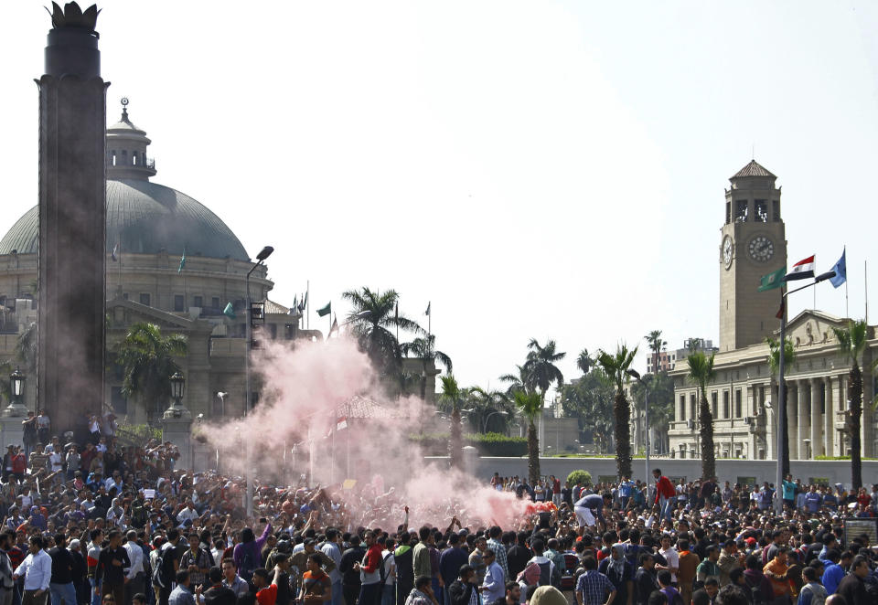 A cloud of red smoke from flares fills the air as supporters of ousted President Mohammed Morsi chant slogans during a demonstration outside Cairo University in Giza, Egypt, Cairo's sister city, Wednesday, March 26, 2014. Clashes have erupted between security forces and students protests at a number of Egyptian universities against mass death sentences issued for hundreds of Islamists in a cursory trial. At Cairo University, hundreds of students who attempted to take their protest outside the campus Wednesday were met with volleys of tear gas from police. Khadiga el-Kholy, a student participating in the protest, said several students were injured. (AP Photo/Ahmed Abdel Fattah, El Shorouk) EGYPT OUT