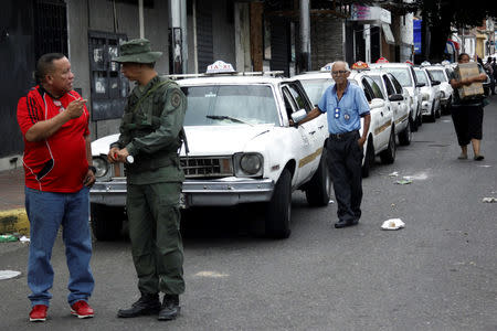 A Venezuelan soldier speaks with a man as motorists queue outside a gas station of the Venezuelan state-owned oil company PDVSA in San Antonio, Venezuela September 4, 2018. REUTERS/Carlos Eduardo Ramirez