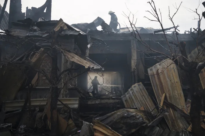 Firefighters work to extinguish a fire at a partially destroyed house.