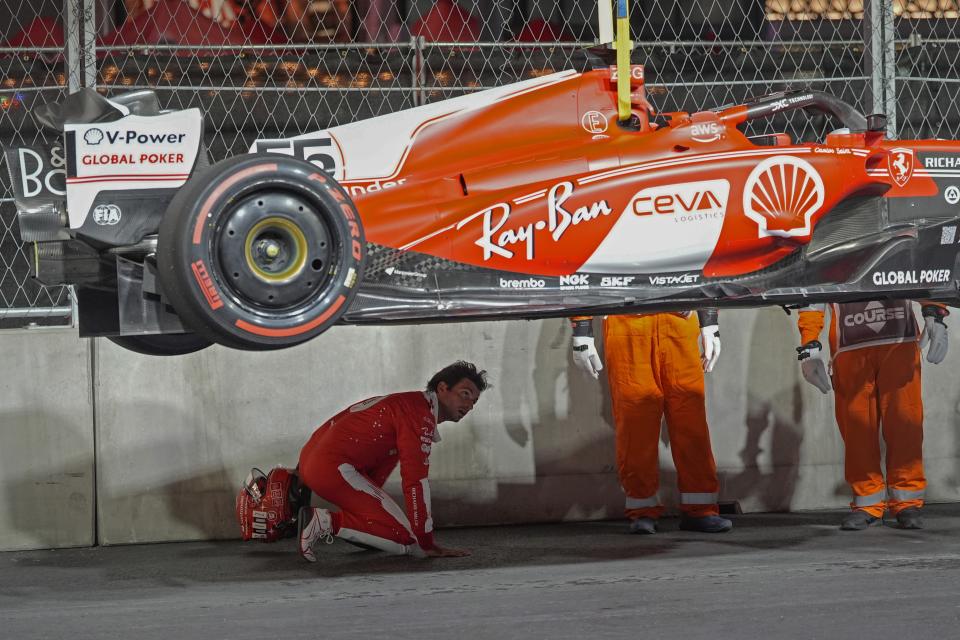 Ferrari driver Carlos Sainz, of Spain, looks at the bottom of his car after running over a manhole cover during the first practice session for the Formula One Las Vegas Grand Prix auto race, Thursday, Nov. 16, 2023, in Las Vegas. (AP Photo/Nick Didlick)