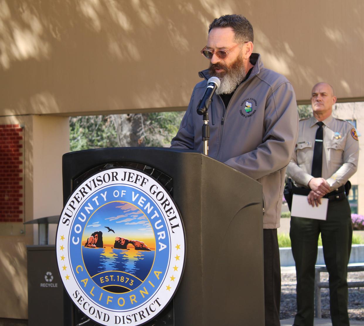 Dr. Christopher Young, Ventura County medical examiner, discusses autopsy results for Brian Ashheim, a homeless man found dead at a Thousand Oaks camp. Listening behind him at the Monday news conference in Thousand Oaks is Police Chief Jeremy Paris.