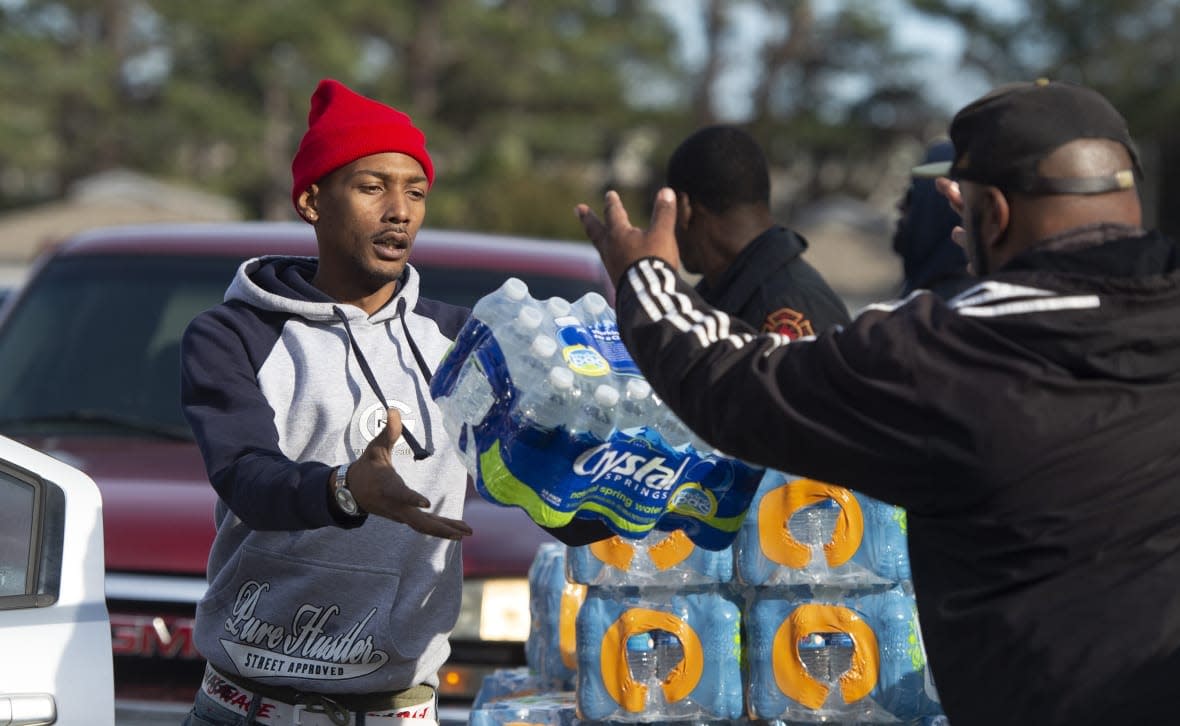 Dontavious Spann, left, with the Mississippi Rapid Response Coalition, and volunteer Preston Alston of Jackson, Miss., help to distribute water to Jackson residents near Northside Drive and Manhattan Road on Dec. 27, 2022. (Barbara Gauntt/The Clarion-Ledger via AP, File)