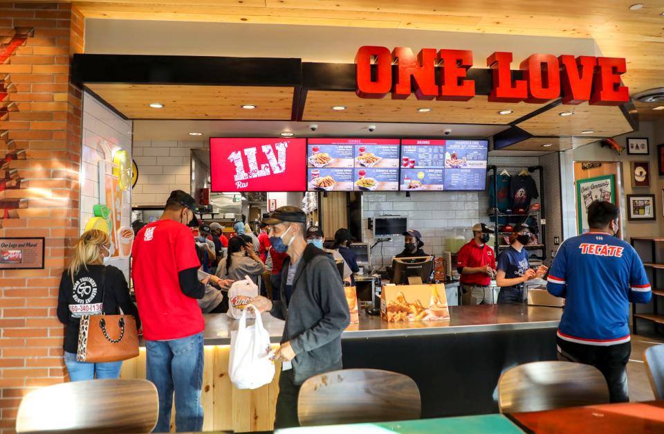 Customers receive their orders from the counter at Raising Cane’s on the restaurant’s soft opening day, Wednesday, Jan. 12, 2022, in Palm Springs, Calif. 