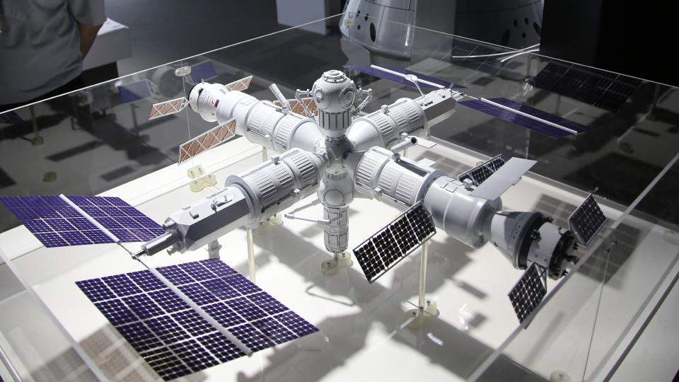   Un modelo de una estación espacial en forma de cruz en una vitrina de cristal en un museo. 